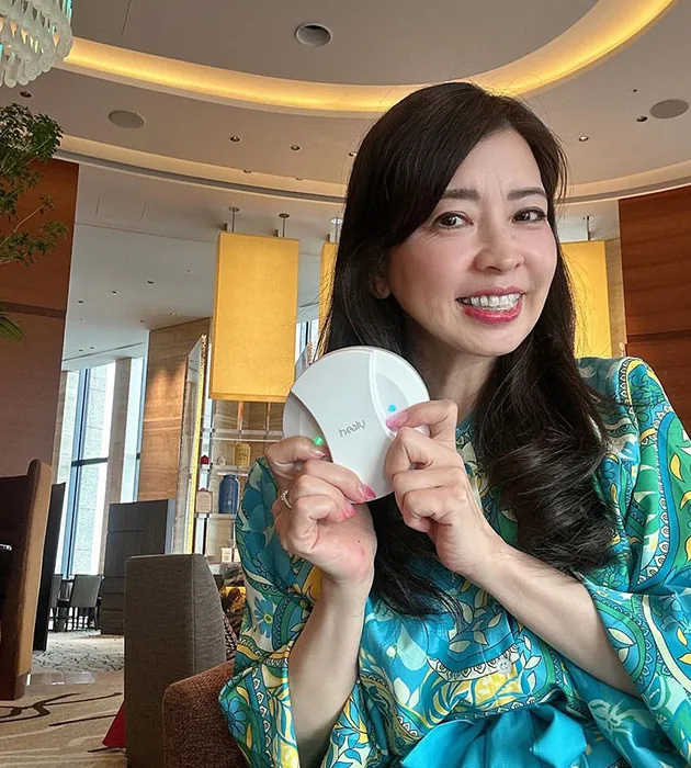 A smiling woman holding MagHealy in a hotel lounge